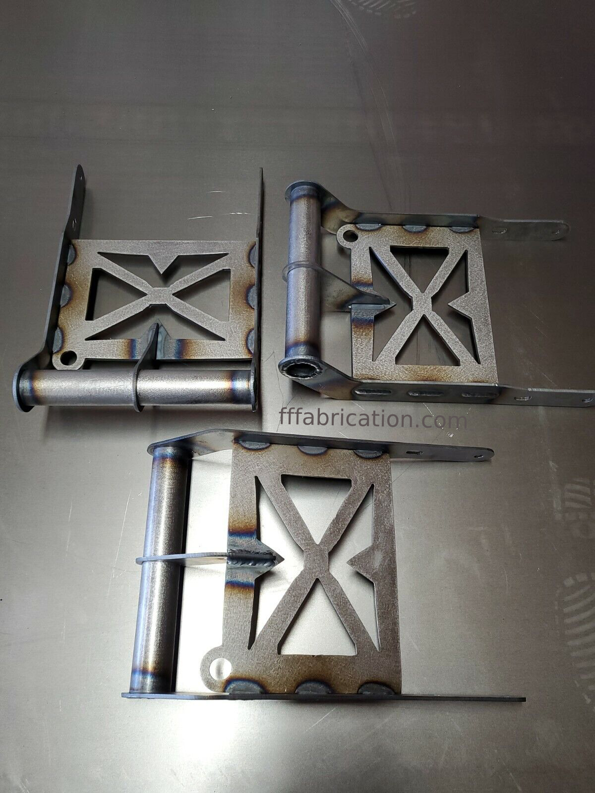 Metal brackets on a reflective surface with 'fffabrication.com' branding.