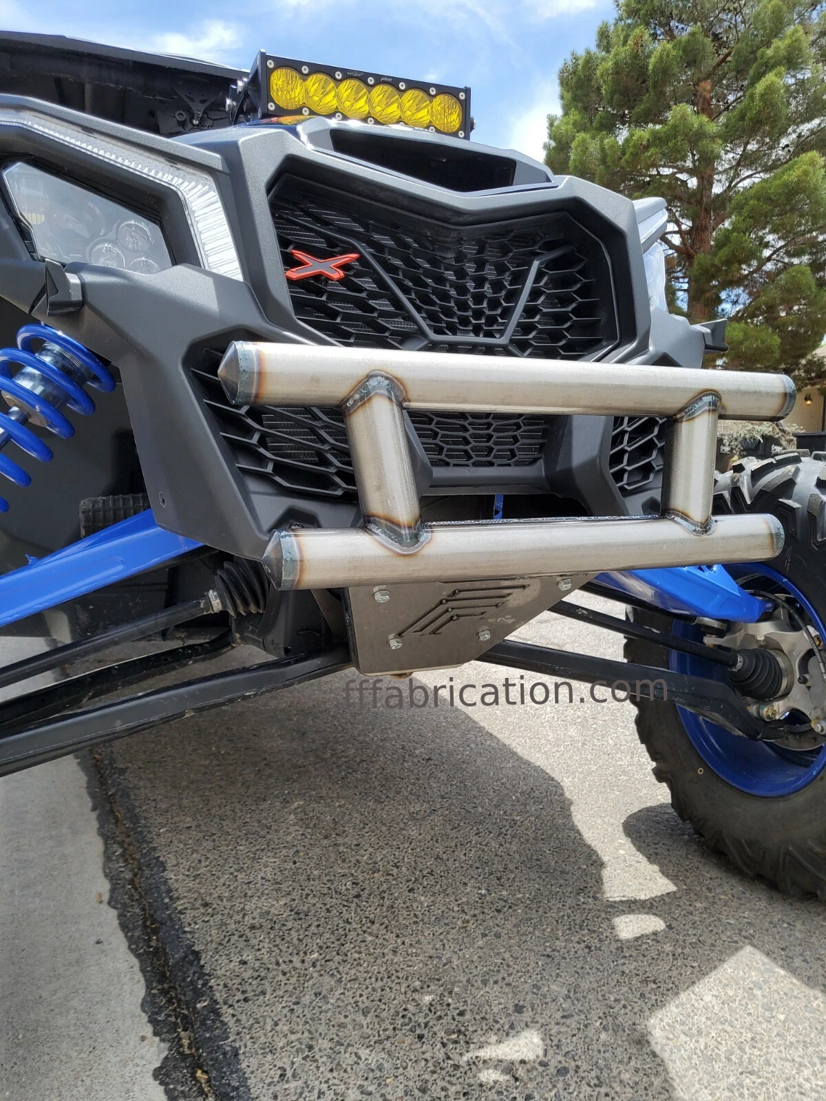 Close-up of a rugged vehicle with a front bumper and LED light bar on a paved surface.
