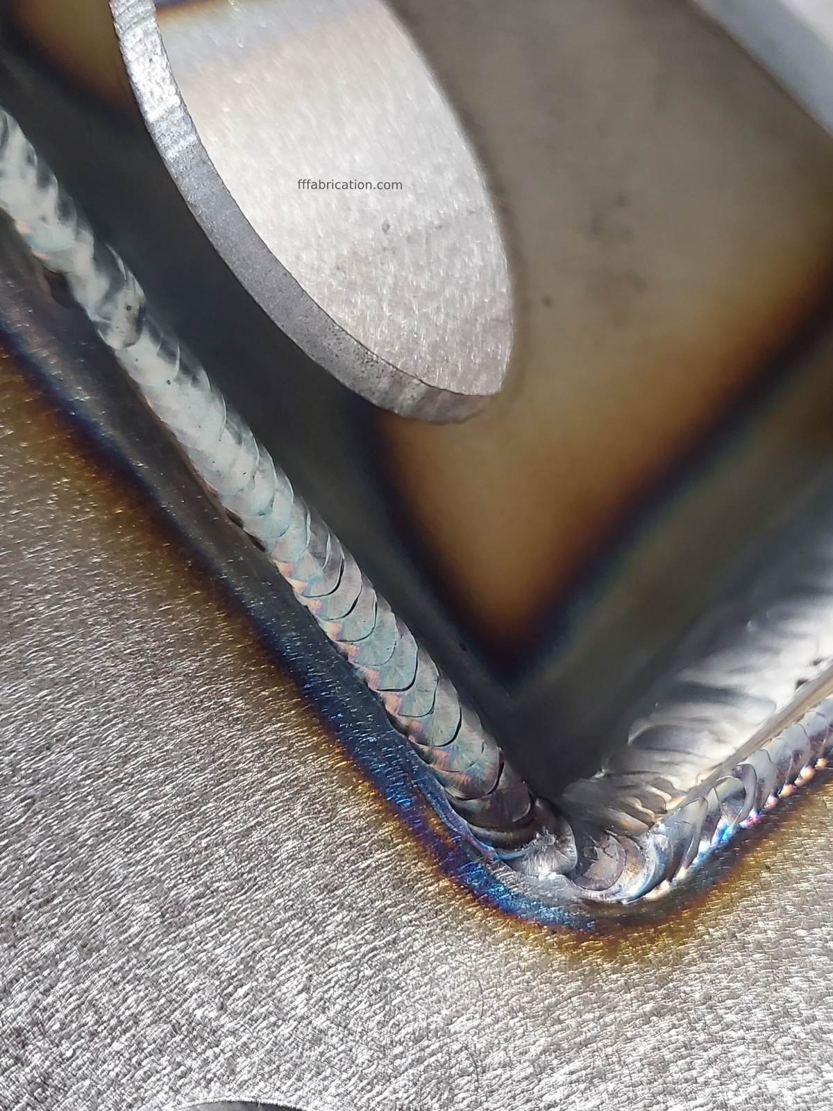 Close-up of a metal weld joint with a tool on top