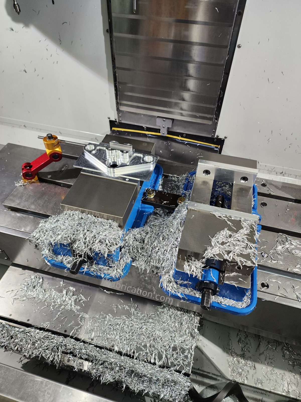Metalworking setup with a milling machine and metal shavings on a workshop table.