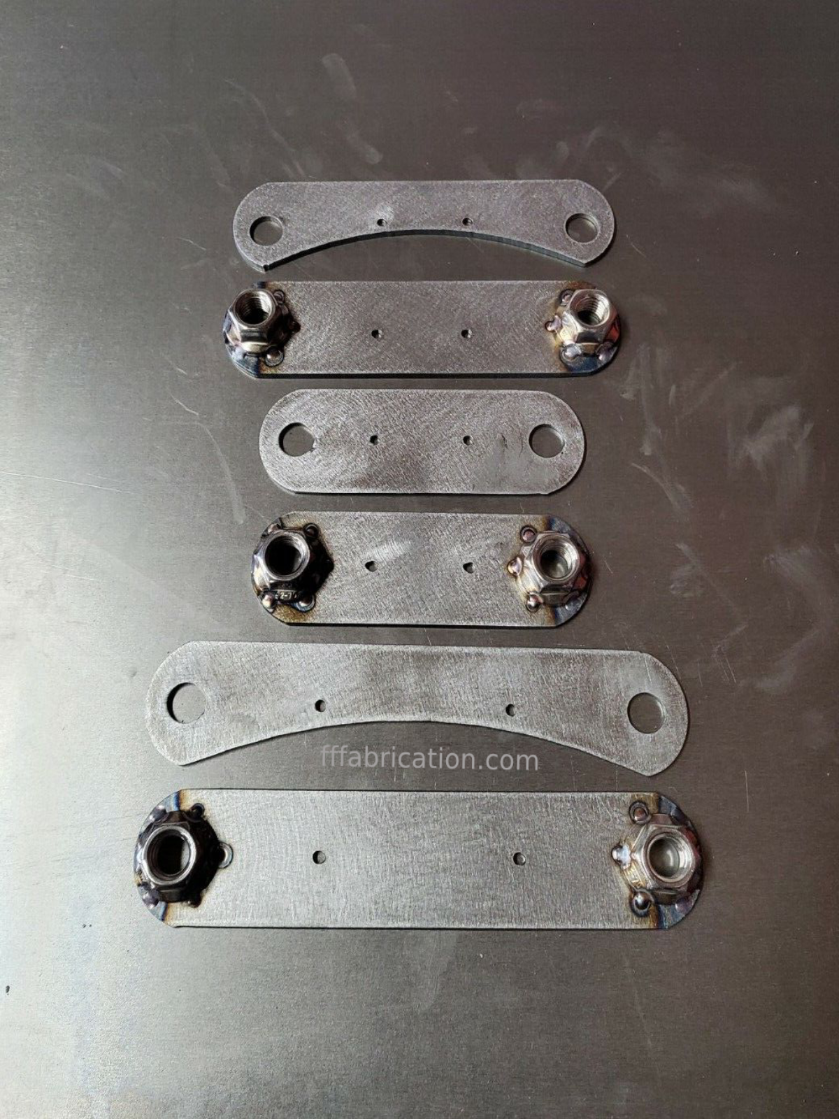 Set of metal brackets with bolts on a metallic surface, featuring 'ffabrication.com' branding.