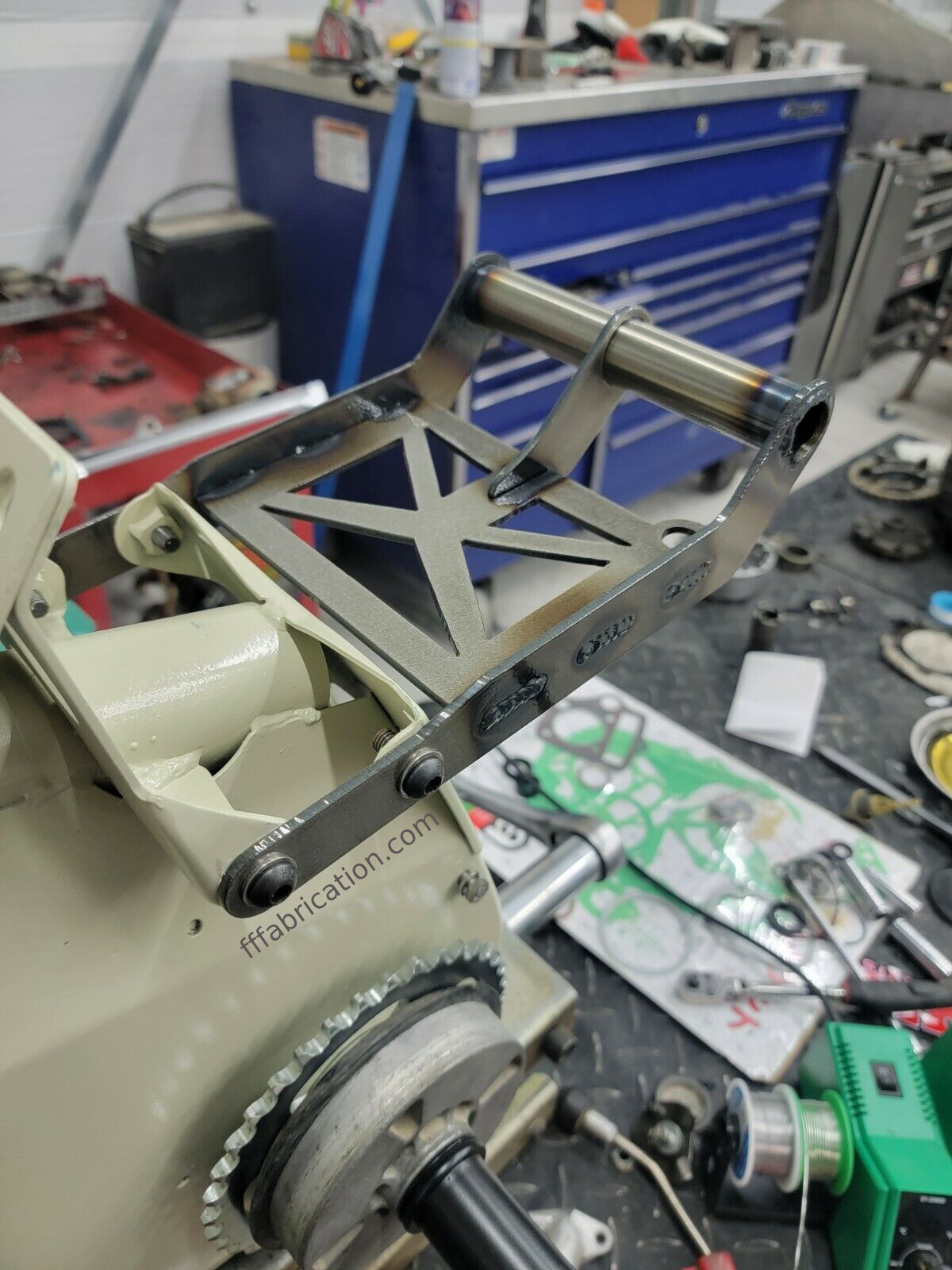 Metal mechanical component on a workbench with tools and equipment in the background