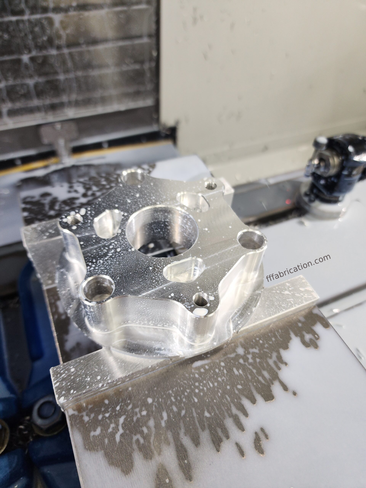 Metal component on a machine with 'fffabrication.com' branding